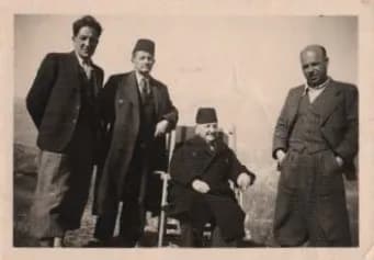 Četvorica muškaraca na otvorenom, jedan sjedi