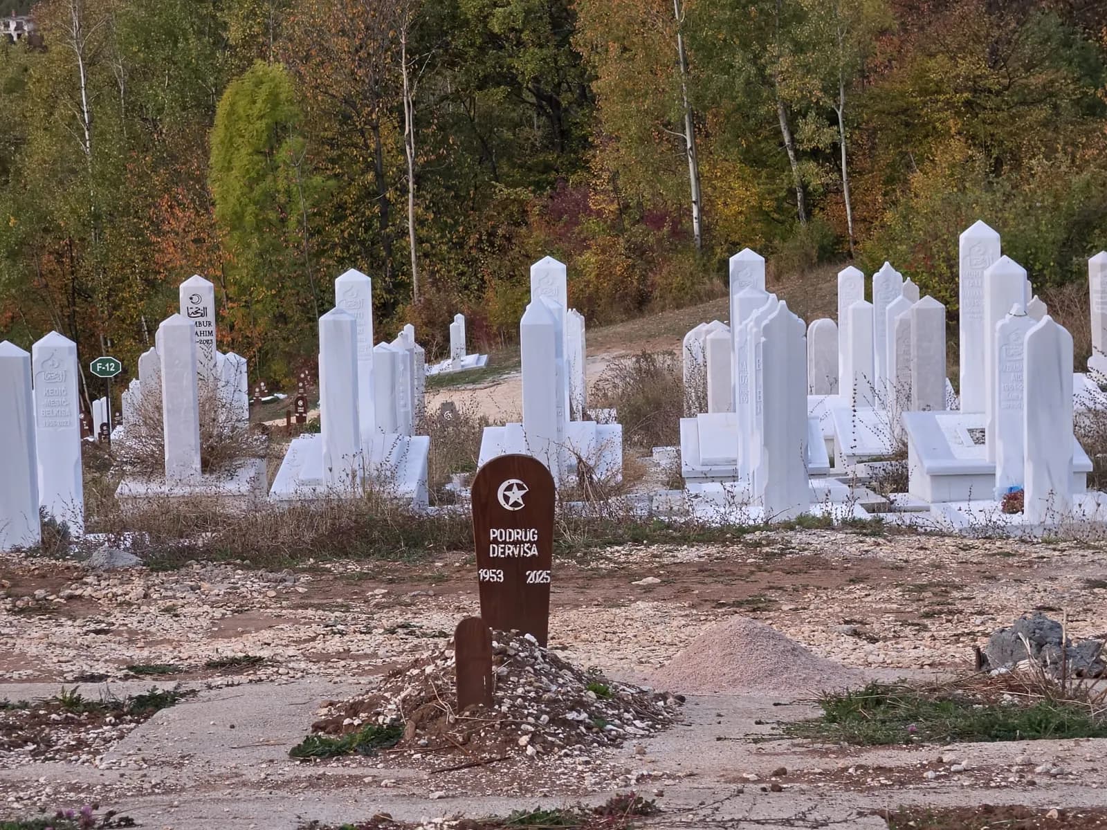 Novi ukopi s drvenim obilježjima, ispred redova nišana